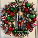 large 60cm artificial spruce wreath embellished with red gold and green decorations with candy cane elements finished off with a central nutcracker