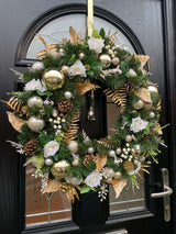 Luxury handmade artificial Christmas wreath in gold with roses, baubles, berries, spruce and pinecones