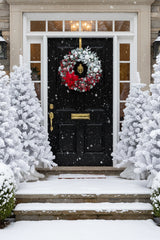Decorative snowy Christmas wreath with red poinsettia, red, white and halogen berries, baubles and ornaments.