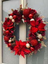 Extravagant red Christmas wreath with large baubles and poinsettias with gold accents.