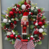 A 60cm Candy cane wreath with lots of foliage and red, green and white baubles, glitz and decorations with a nutcracker at the centre.