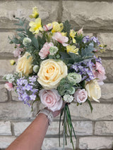 A tall, artificial hand tied artificial flower arrangement in pretty pastel shades, featuring roses, blossom and thistles by Alana’s floristry