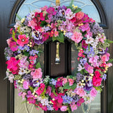 Large pink and purple wreath with faux flowers, perfect for year-round decor, showcasing pansies and vibrant textures.