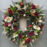 Winter artificial wreath in mulberry and ivory with dried roses and hellebore.