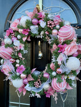 Handmade artificial Christmas wreath using luxury faux florals and baubles and glitter accents in pink and white