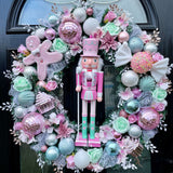 A pink and mint luxury Christmas wreath featuring a coordinating nutcracker centrepiece. Big artificial sweets and a large pink gingerbread man with pink disco ball baubles sound completely OTT but work so elegantly and beautifully within this wreath. Mint and pink roses and baubles with glitter sprays finish off this opulent yet fun wreath perfectly.