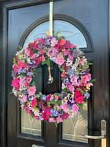 Large luxury pink and purple summer wreath with pansies and roses, showcasing vibrant blooms on a front door.