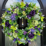 Artificial Decorative wreath with green and purple flowers on a door