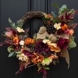 Autumn-themed wreath with colorful flowers and leaves on a dark background