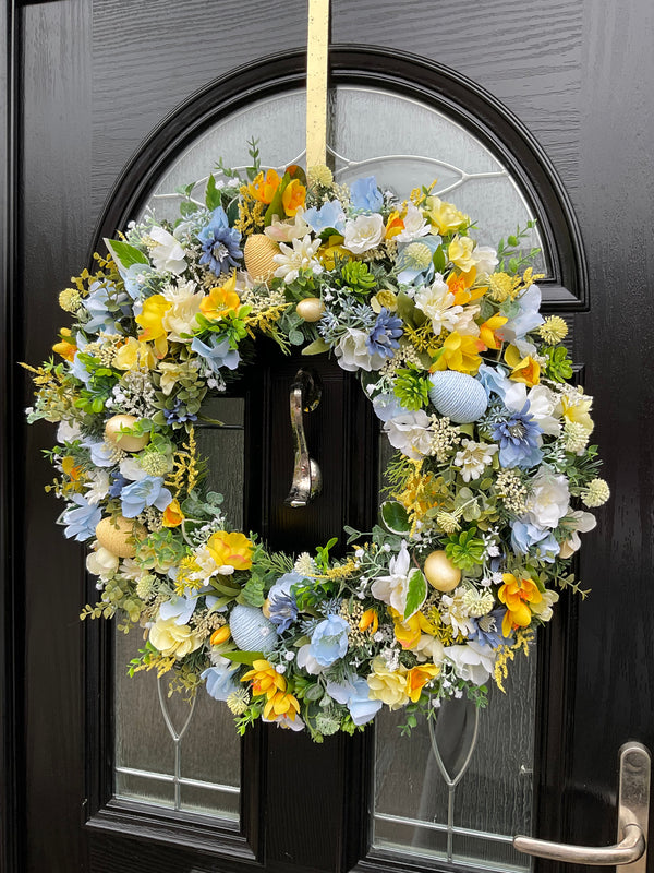 Luxury handmade pastel spring wreath featuring yellow, blue cosmos and faux pastel eggs, perfect for Easter decor.