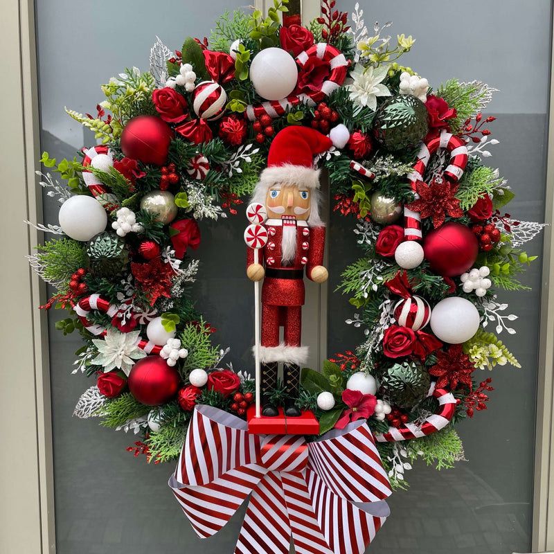 A 60cm Candy cane wreath with lots of foliage and red, green and white baubles, glitz and decorations with a nutcracker at the centre. 