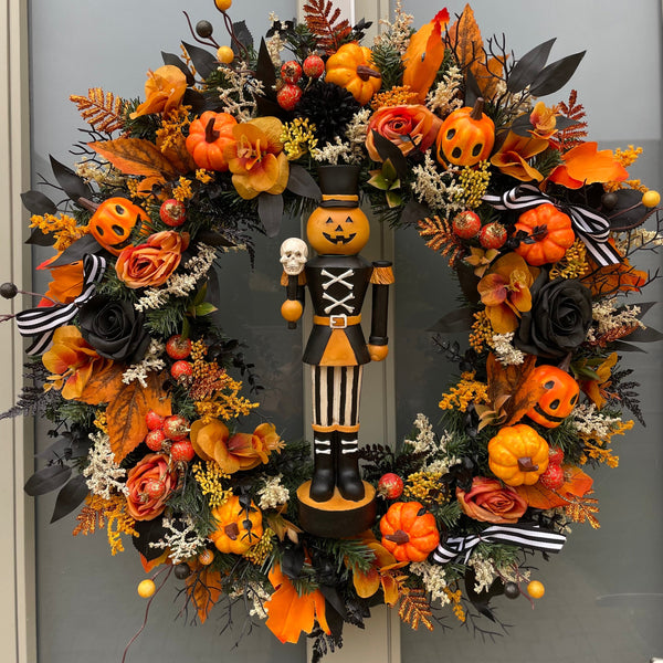 Halloween-themed wreath with pumpkins, flowers, and a pumpkin nutcracker figure in the centre 