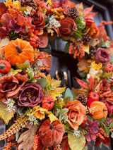Close up of luxury autumn velvet pumpkin wreath showing berry, foliages and pumpkin details in rich yellows, oranges and browns 