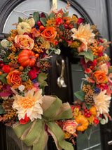 Close up of luxury artificial Autumn wreath in rustic shades with bow and pumpkins 
