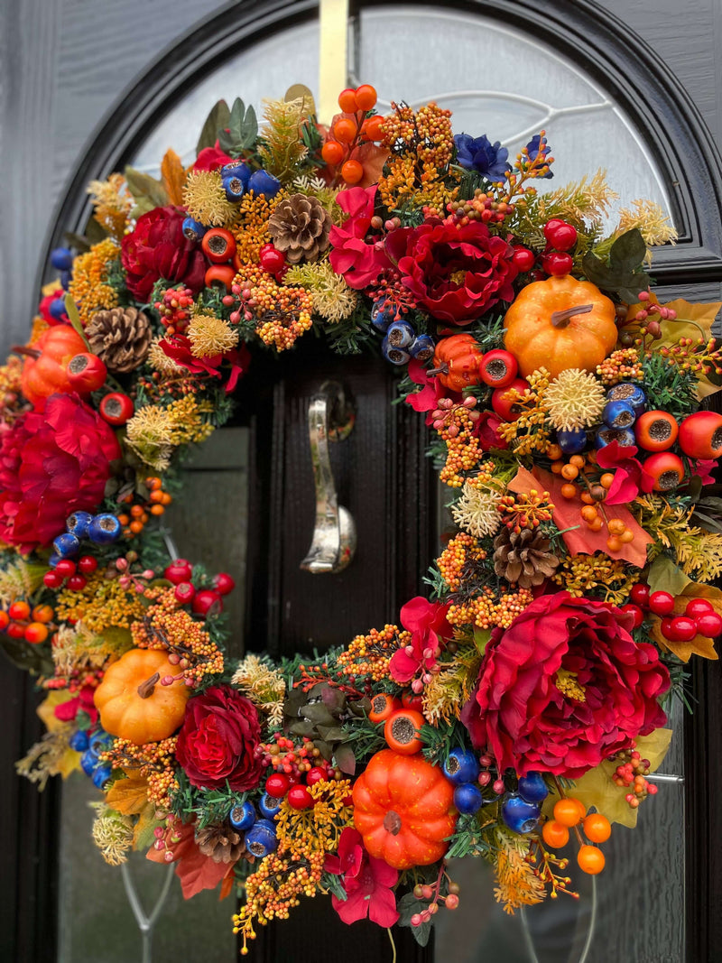 Orange, red and blue autumn wreath featuring pumpkins, berries and pine cones 