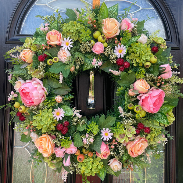 Peach pink floral wreath with faux raspberries and green hip berries with bright green foliage. Measuring a large 60cm.