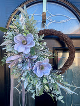 A luxury artificial half wreath design reaching 60cm in length. Featuring large grey magnolia, a silver grey bow, hydrangea and an abundance of flocked foliage.