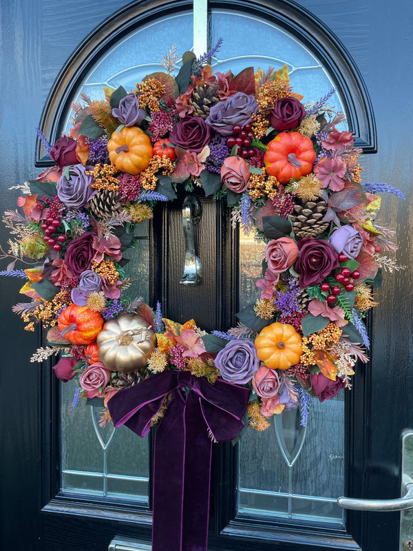 Artificial autumn wreath using shades of oranges, plums and purples featuring berries and pumpkins.