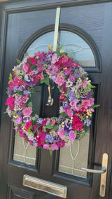 Large luxury pink and purple wreath with vibrant faux flowers on a black door, perfect for year-round decor.