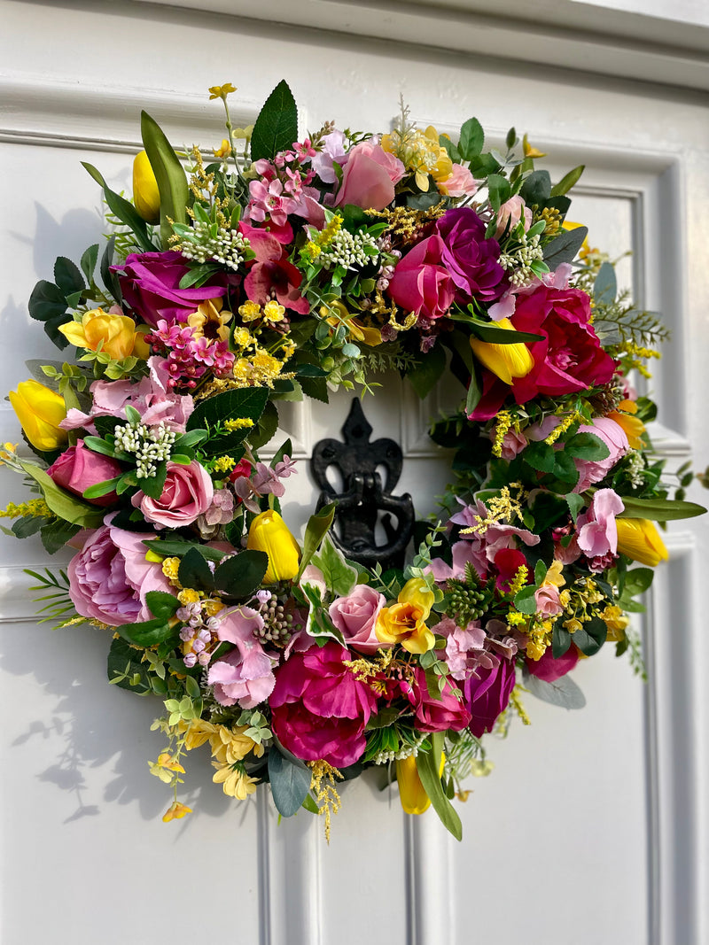 A luxury large pink and yellow spring tulip wreath with an abundance of florals from hydrangeas to roses to astilbe to eucalyptus.